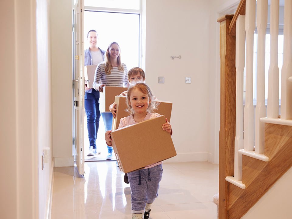 Family Carrying Boxes Into New Home On Moving Day